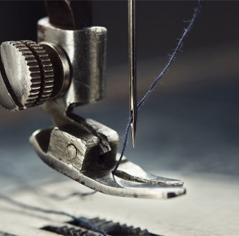 Zoomed-in picture of a threaded needle in a sewing machine.