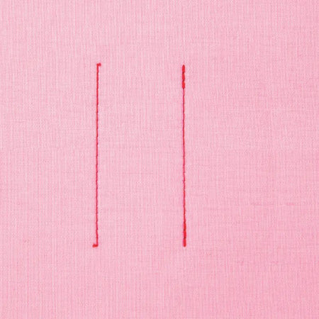 Two vertical red stitches made by a Juki HZL-80HP-A