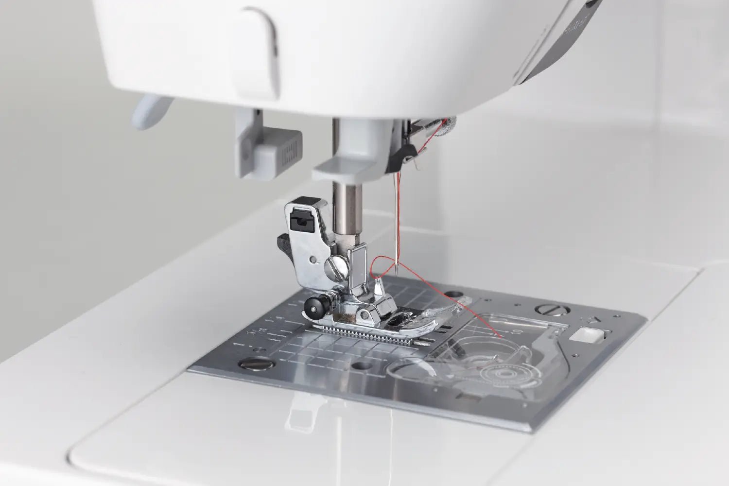 Close-up of a Juki HZL-G220 needle and presser foot on a white background