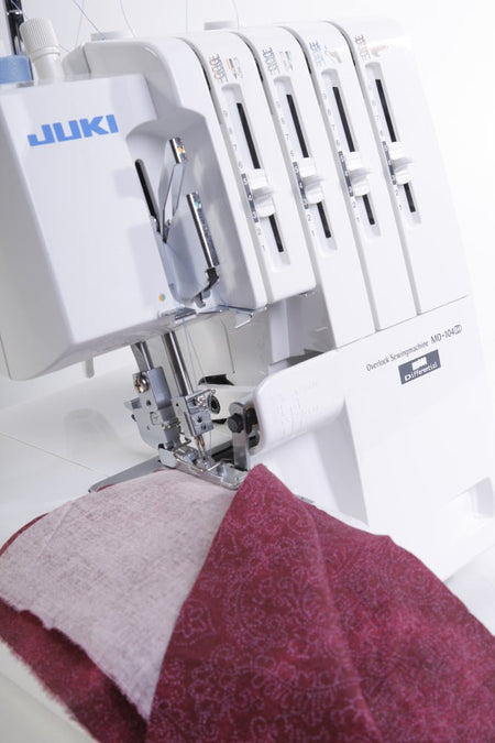 Close-up of a Juki MO-104D sewing red fabric