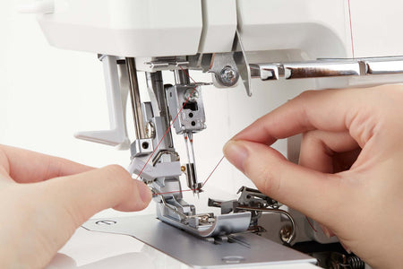 Close-up of a Juki MO-2800 sewing machine with hands adjusting the thread