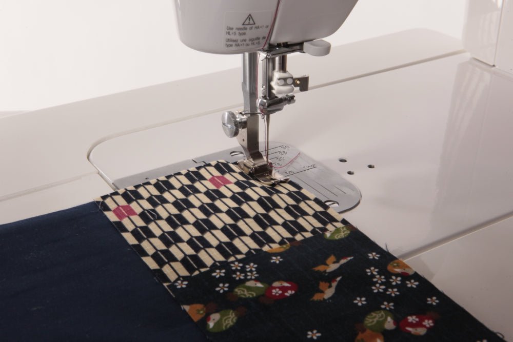 Juki TL-2000Qi Sewing machine with a piece of fabric featuring a colorful pattern on a white background